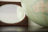Beveled glass surface of the small wood mirror reflecting a vintage globe.