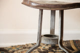 Textured galvanized steel legs and industrial base of the antique milking stool.