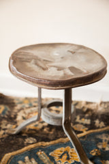 Antique galvanized steel milking stool top, showing its aged industrial patina and wear.