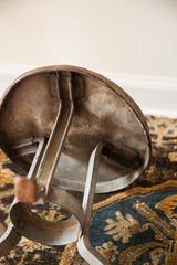 Antique industrial milking stool's galvanized steel underside and sturdy legs.
