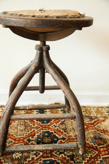 Aged dark wooden legs of an antique Victorian industrial stool with visible iron screw.