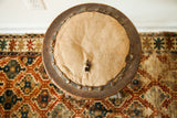 Distressed round seat of Victorian industrial stool, torn fabric exposing horsehair, metal studs.