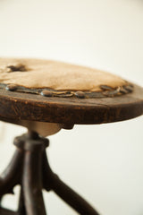 Victorian industrial stool seat edge with worn leather trim, exposed horsehair, aged wood.