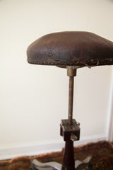 Distressed brown leather seat and original nail trim on antique Shuron medical stool.