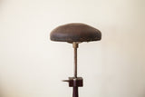 Cracked brown leather seat edge with original nail trim and adjustment lever.