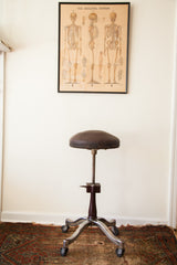 Original steel casters, splayed metal base, and brown central post of the Shuron medical stool.