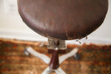 Aged brown leather seat surface with visible cracking on the vintage Shuron stool.