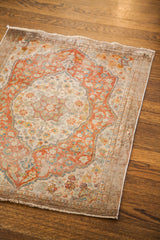 Antique Tabriz silk rug corner showing light floral pattern, secured border, and fringe.