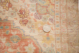 Close-up of antique silk Tabriz rug's fine weave, with light floral motifs and a quarter for scale.