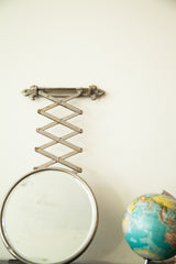 Fleur de lis hardware and metal accordion arm of the vintage beveled glass shaving mirror.
