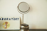 Antique shaving mirror, round beveled glass, black backing, brush, fluted metallic base.