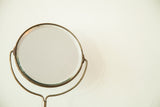 Round beveled glass and aged metal frame of the antique shaving mirror.
