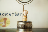 Aged Sana-Genic shaving brush in a perforated antique metal stand.