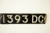 Vintage black and silver Art Deco British license plate with raised numerals and letters.