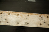 Vintage British license plate back, showing worn metallic texture and fasteners.
