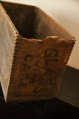 Distressed wooden crate detail with 'GLASS WITH CARE' inscription and worn top edge.