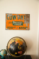 Rusty, chipped orange metal sign with green 'Brown's Feeds' text, lower right.