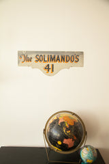 Vintage Deco Solimando's house sign, black, orange, ivory text, displayed above two globes.