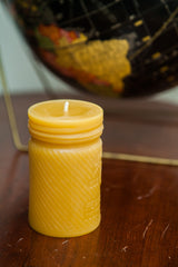Yellow beeswax candle showing concentric cap design and diagonally swirled body.