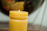 Golden yellow beeswax candle top with molded jar cap and swirled body texture.