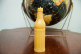 Honey yellow beeswax candle, vintage soda bottle shape with crosshatching and ridged texture.