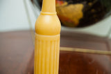 Light yellow beeswax candle with antique bottle design, featuring crosshatch texture and vertical ridges.