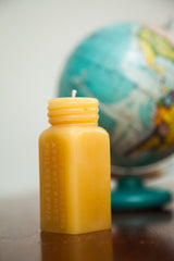 Amber beeswax candle with molded 'APOTHECARIES PHILADELPHIA' text and screw top.
