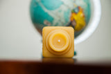 Boxy antique inkwell design of a natural beeswax candle from the top view.