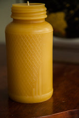 Threaded neck and embossed harlequin pattern on a golden beeswax candle.
