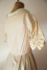 Elegant ruched sleeve and tailored back of a 1950s ivory silk satin dressing gown.
