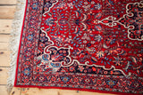 Vintage Bijar rug corner: cherry red field, intricate blue floral pattern, and cream fringe.