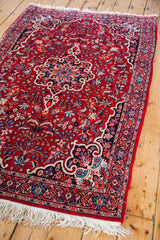 Cherry red Bijar rug with central floral medallion, intricate navy, and cream vine motifs.