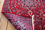 Folded corner of a Vintage Bijar rug, revealing vibrant floral patterns and hand-knotted reverse.