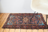 Vivid aqua spandrels, indigo field, and madder red motifs on this mid-century Hamadan rug.