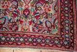 Traditional Sarouk rug corner with creamy ivory field and detailed red, aqua borders.