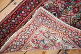 Folded Sarouk rug displaying its unusual ivory field, aqua, red motifs, and detailed borders.