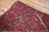 Folded antique Tekke rug showing distressed pile with raspberry red and blue guls.