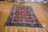 A collector's antique Persian Bijar rug with a complex harshang pattern, seen from an angle.