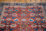 Traditional Harshang floral motifs in blue and pink on an antique Persian Bijar's rust-red field.