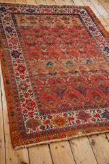 Aged fringes and vibrant geometric motifs on the corner of the antique Malayer rug.