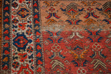Antique Malayer rug detail with ruby red field, sapphire blue border, and traditional geometric motifs.