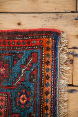 Close-up of antique Kurdish tribal rug border, vibrant red, blue, orange patterns, and fringe.