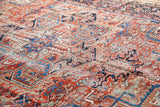 Bold geometric Heriz pattern with time-softened red, blue, and cream tones.