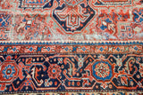 Patinaed geometric patterns in red, navy, and sky blue on a vintage Heriz rug.