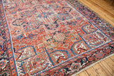 Distressed pile and geometric border of a vintage Heriz rug in red and blue.