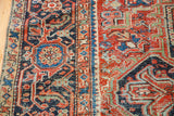 Intricate geometric patterns and rich colors on a vintage Heriz rug, showing visible threadbare wear.