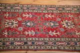 Red ground featuring geometric patterns in navy blue, ivory, and light blue.