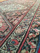 Distressed geometric patterns with coral, teal, and cream colors on an antique Northwest Persian runner.