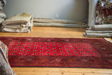 Deep cranberry red field of a vintage Bokhara rug with charcoal geometric patterns.
