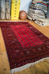 White fringe and intricate geometric borders of a cranberry red vintage Turkmen Bokhara rug.